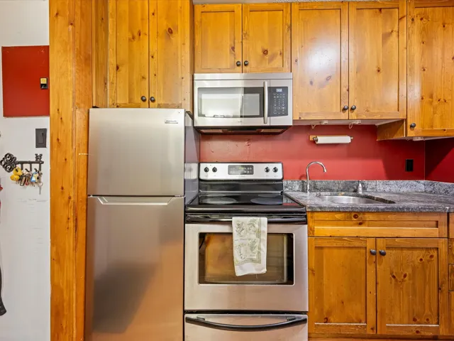 Kitchen with appliances with stainless steel finishes, brown cabinetry, and dark countertops