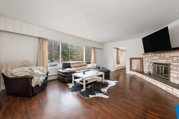 Living area with baseboard heating, a fireplace, wood finished floors, and a baseboard radiator