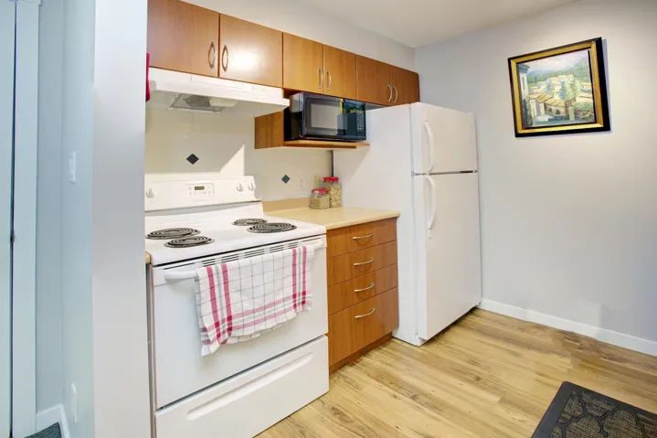 Kitchen featuring white appliances, brown cabinets, under cabinet range hood, and light wood-style floors