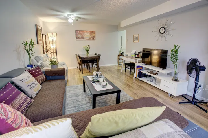 Living area featuring light wood-type flooring, a ceiling fan, and a textured ceiling