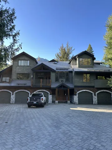View of front facade with decorative driveway, stone siding, a garage, and a metal roof