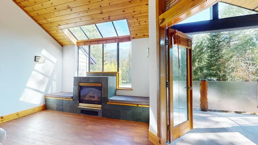 Unfurnished room with lofted ceiling, healthy amount of natural light, wood ceiling, wood finished floors, and a tile fireplace