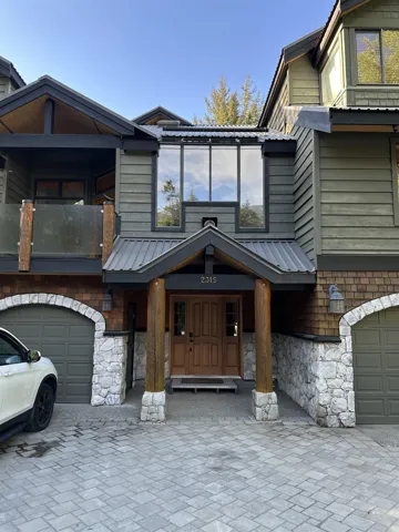 View of front of property featuring stone siding, a garage, and decorative driveway