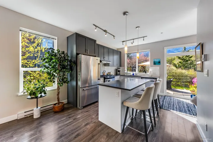 Kitchen with under cabinet range hood, stainless steel appliances, dark wood-type flooring, and a kitchen island