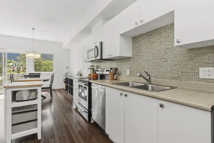Kitchen featuring white cabinetry, stainless steel appliances, a dual basin sink, and a horizontal linear mosaic tile backsplash