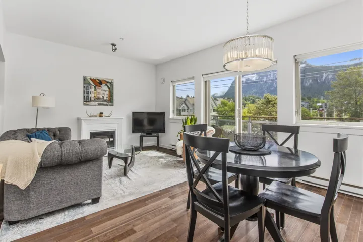 Open-concept living area with wood-finish flooring, a white fireplace, and a dining area illuminated by a decorative chandelier