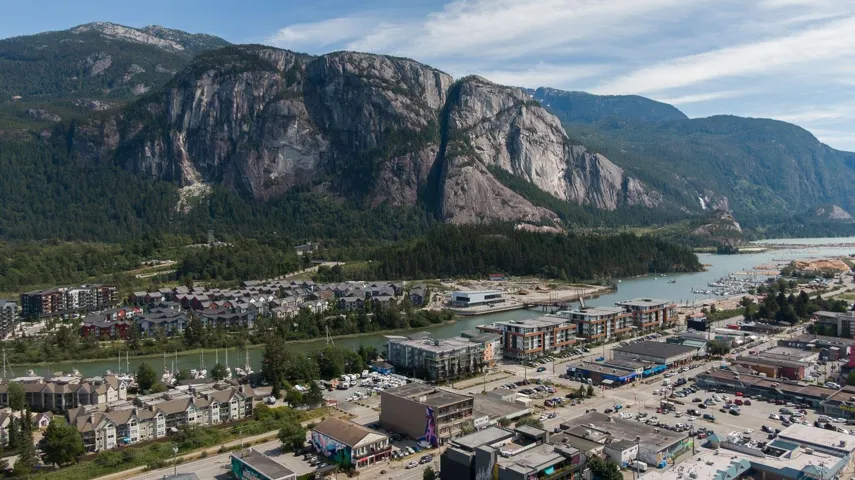 Expansive aerial capturing the surrounding natural landscape, including a prominent mountain range with forested slopes