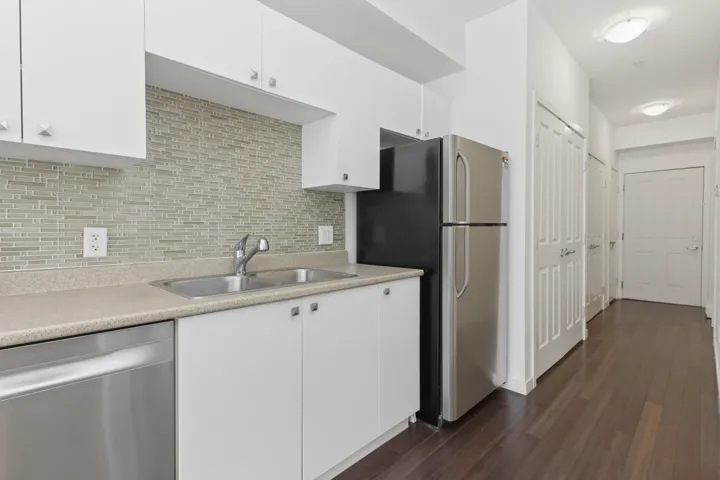 Kitchen featuring white cabinetry, a dual basin stainless steel sink, a stainless steel dishwasher, and a refrigerator