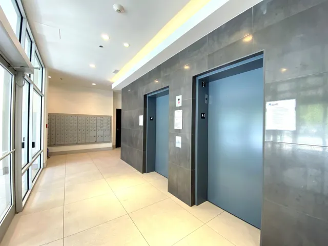 Hall featuring tile walls, elevator, mail area, light tile patterned floors, and recessed lighting