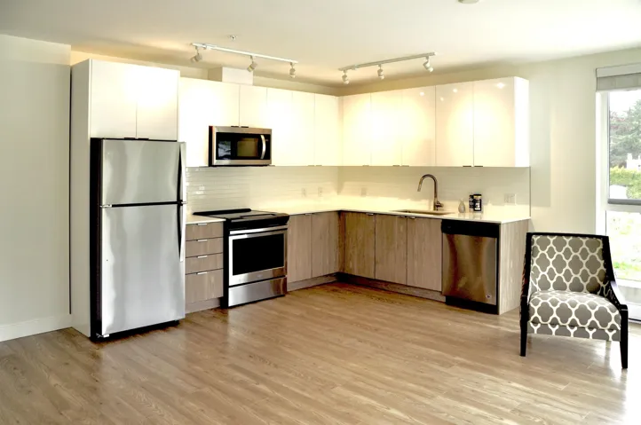 Kitchen featuring appliances with stainless steel finishes, light countertops, modern cabinets, light wood-style floors, and tasteful backsplash