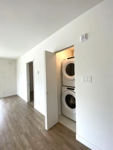 Laundry area featuring stacked washing machine and dryer and wood finished floors