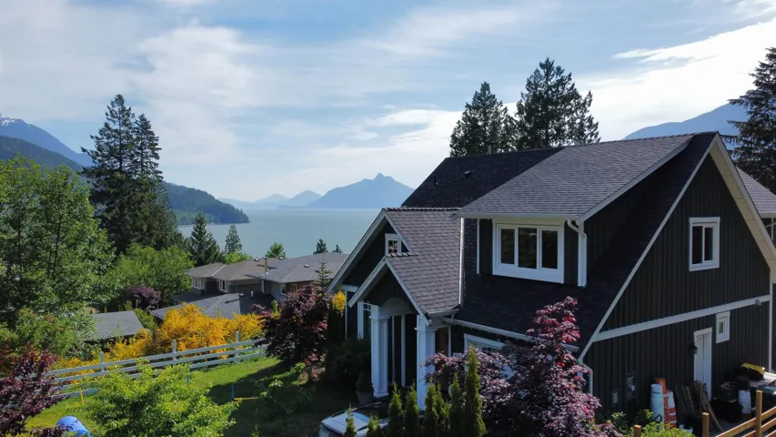 View of side of property with a shingled roof and a water and mountain view