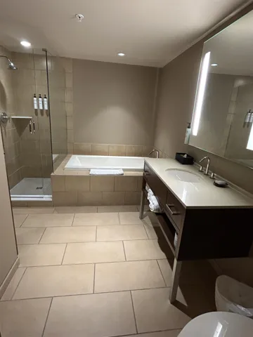 Contemporary bathroom featuring an integrated shower and soaking tub, a single vanity with a solid surface countertop, and large format floor tiling