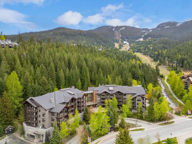 Multi-story building featuring stone and wood-look siding, gabled rooflines, and multiple balconies