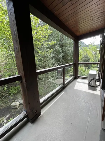 Private balcony featuring wood-finish ceiling, robust wood beams, and a glass railing system