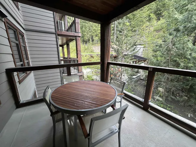 Private balcony featuring glass railings, concrete flooring, and a natural wood ceiling