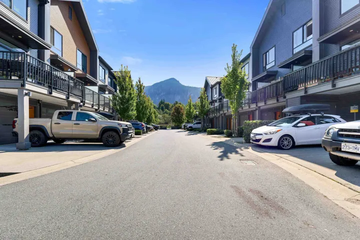 Modern townhome architecture featuring multiple balconies with black railings, covered parking, and mountain scenery