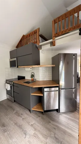 Compact kitchen featuring wood-finish flooring, dark gray cabinetry, wood countertops, and a white subway tile backsplash