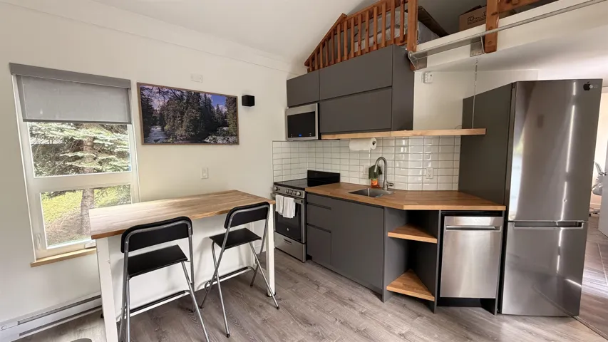 Modern kitchen featuring gray cabinetry, light wood-finish countertops, and a subway tile backsplash