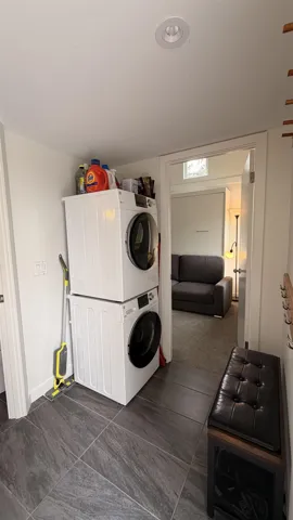 Laundry area featuring a stacked washer and dryer, recessed lighting, and dark grey large-format tile flooring