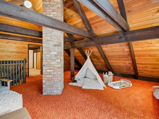 Recreation room featuring lofted ceiling with beams, wood walls, wooden ceiling, and carpet