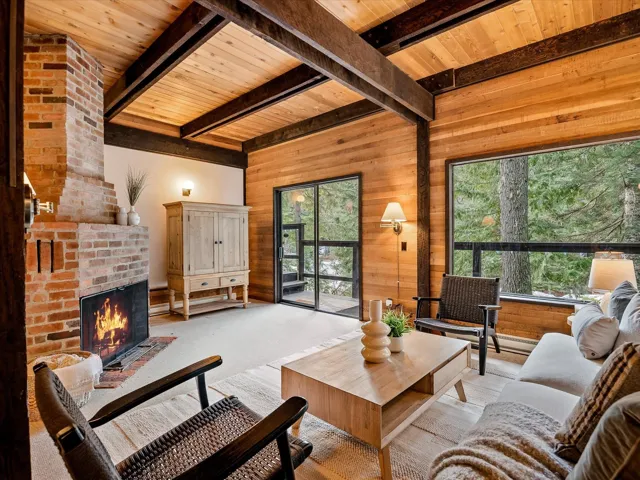 Living room with wooden ceiling, wooden walls, a fireplace, and beamed ceiling