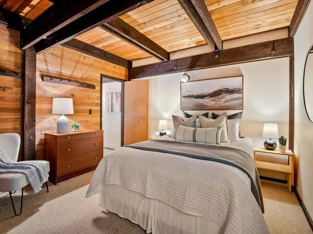 Bedroom with wooden ceiling, carpet flooring, beam ceiling, and wooden walls