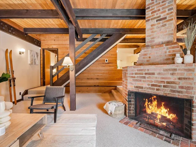 Interior space featuring stairs, an outdoor brick fireplace, wood ceiling, and wooden walls