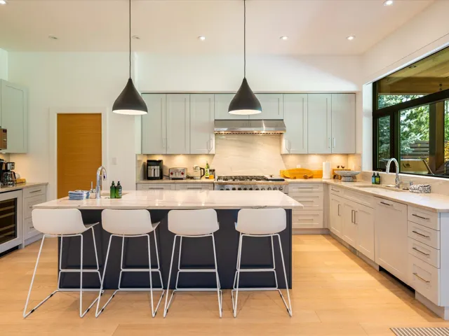Kitchen featuring pendant lighting, a kitchen island with sink, light stone countertops, tasteful backsplash, and recessed lighting