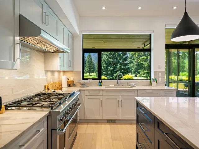 Kitchen featuring light stone countertops, double oven range, under cabinet range hood, light wood finished floors, and recessed lighting