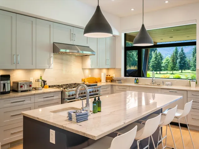 Kitchen with hanging light fixtures, light stone countertops, a kitchen breakfast bar, double oven range, and under cabinet range hood