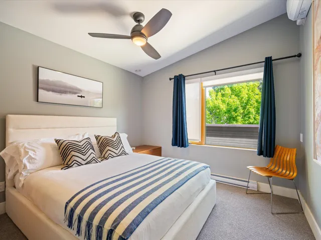 Bedroom with vaulted ceiling, carpet flooring, a baseboard heating unit, and a ceiling fan
