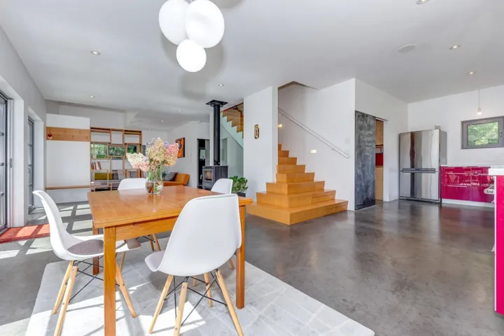 Dining area with concrete flooring, healthy amount of natural light, stairway, recessed lighting, and a wood stove