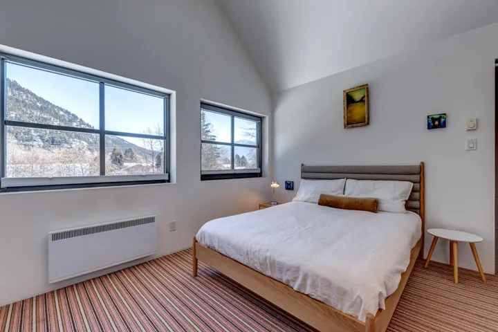 Bedroom with radiator heating unit, vaulted ceiling, and a mountain view