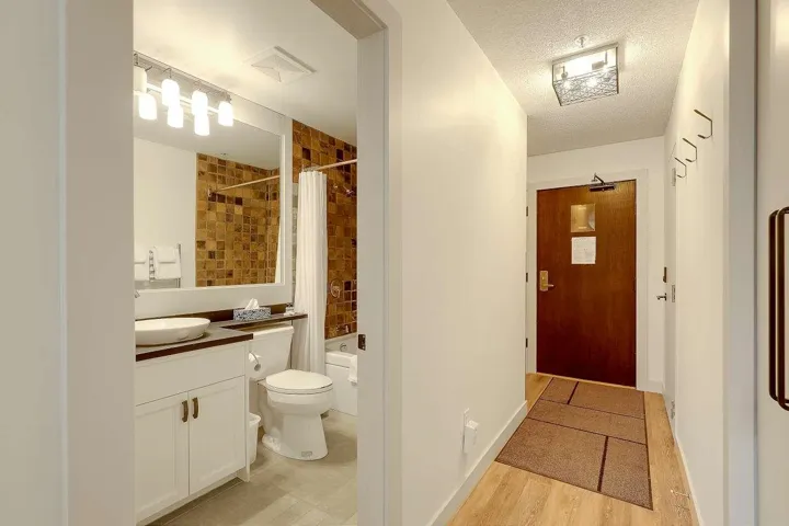 Bathroom with vanity, a textured ceiling, shower / tub combo, and light wood-style floors