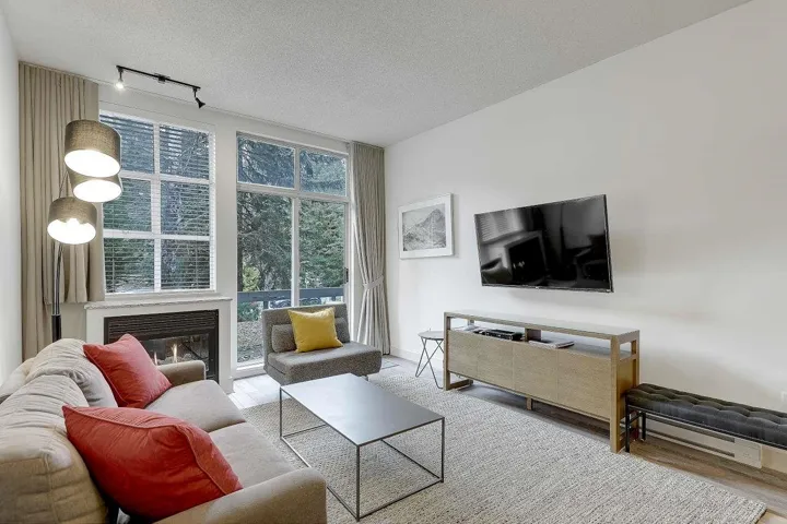 Living area featuring wood finished floors, track lighting, a textured ceiling, and a glass covered fireplace