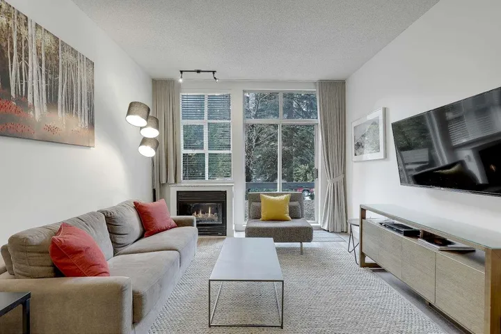 Living room with a textured ceiling, a glass covered fireplace, track lighting, and wood finished floors