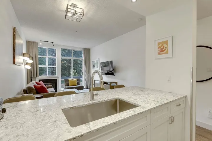 Kitchen with light stone counters, open floor plan, white cabinets, a textured ceiling, and a glass covered fireplace