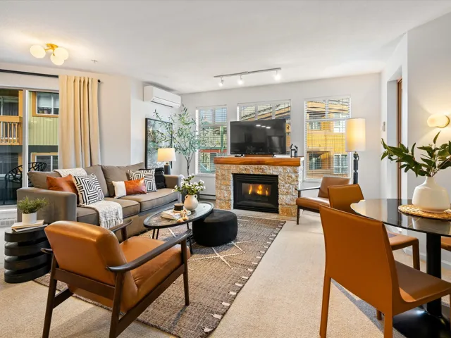 Living area with a stone fireplace, light carpet, healthy amount of natural light, and a wall unit AC
