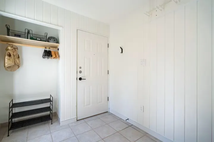 Doorway with tile patterned flooring and wooden walls