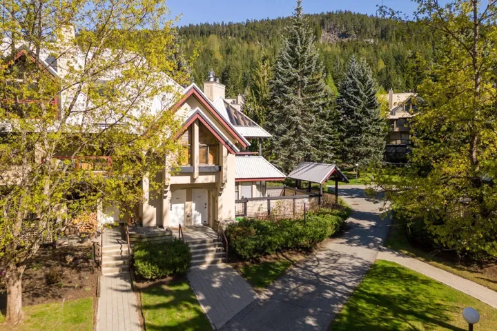 View of front facade with a forest view, a metal roof, and a chimney