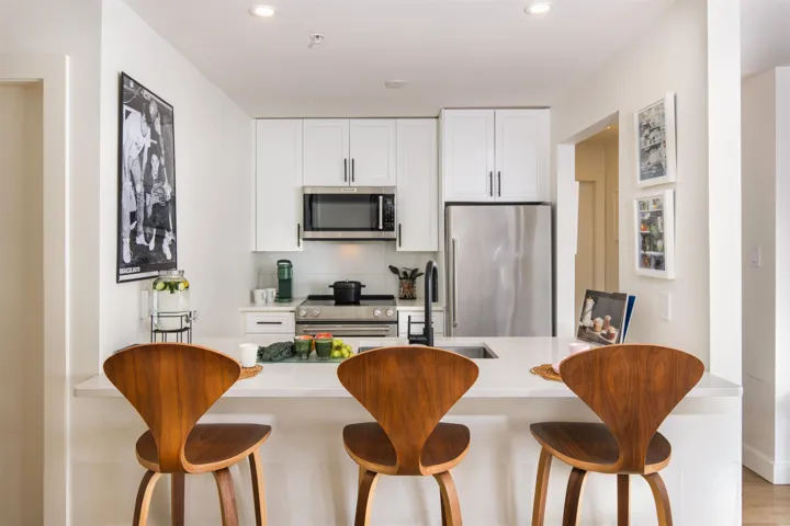 Kitchen featuring tasteful backsplash, a kitchen bar, white cabinets, stainless steel appliances, and recessed lighting