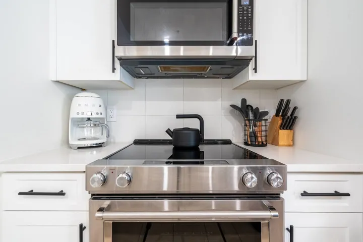 Kitchen featuring appliances with stainless steel finishes, white cabinets, and decorative backsplash