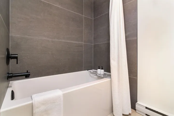 Bathroom with a baseboard heating unit and shower / bath combo