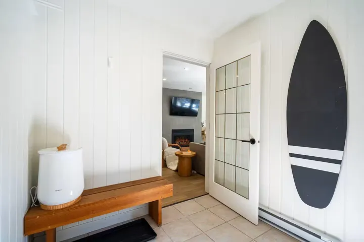 Mudroom with baseboard heating, tile patterned floors, and a lit fireplace
