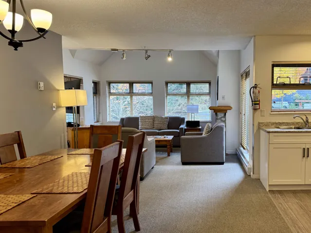 Dining room featuring vaulted ceiling, a textured ceiling, a chandelier, light carpet, and a baseboard radiator