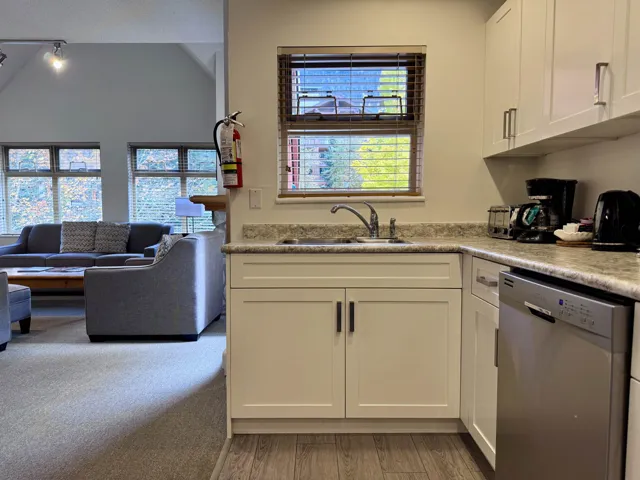 Kitchen with white cabinets, dishwasher, light countertops, and open floor plan