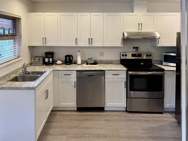 Kitchen with appliances with stainless steel finishes, white cabinetry, and light countertops
