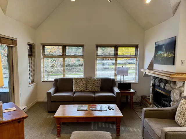 Living room with carpet, a fireplace, and high vaulted ceiling