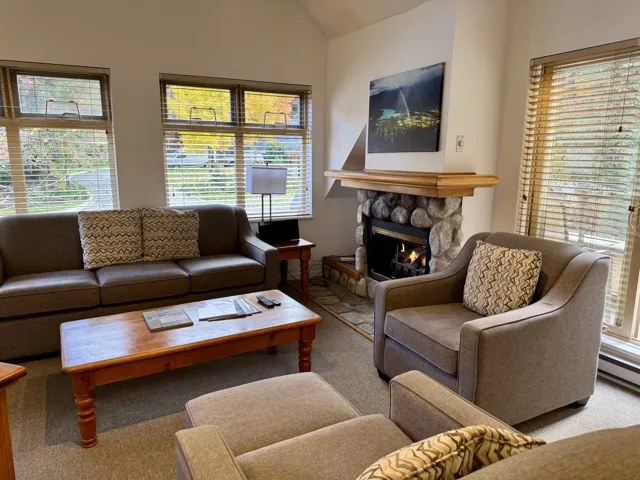 Carpeted living room with healthy amount of natural light, a fireplace, and lofted ceiling